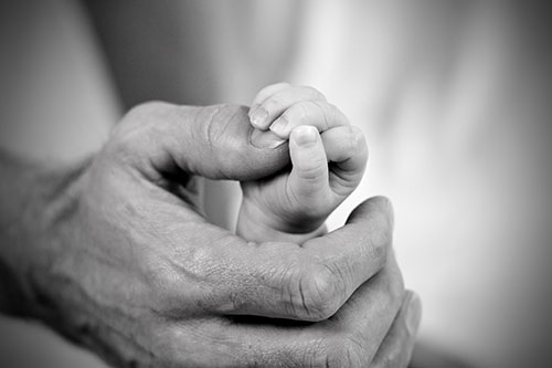 Baby der holder en nybagt far i hånden